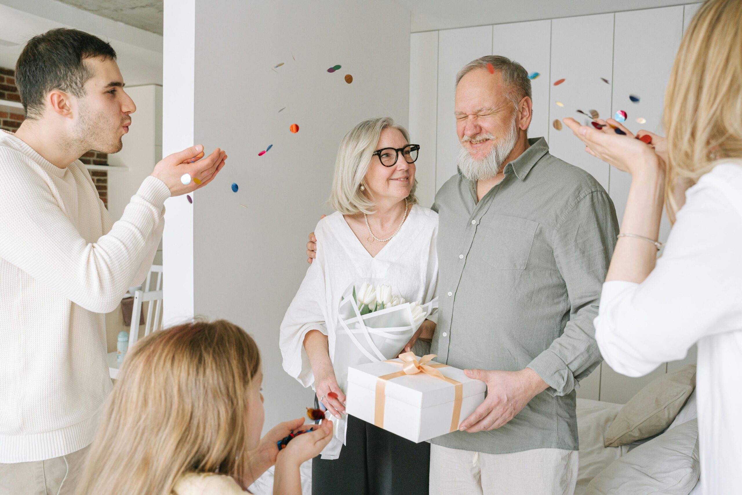 Happy elderly couple receives gifts and love from family during an indoor celebration.